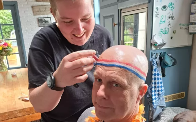 Dula tekent een Nederlandse vlag op haar kale vader's hoofd