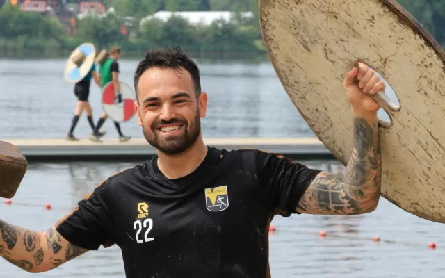 Nino lacht terwijl hij een schild omhoog houdt